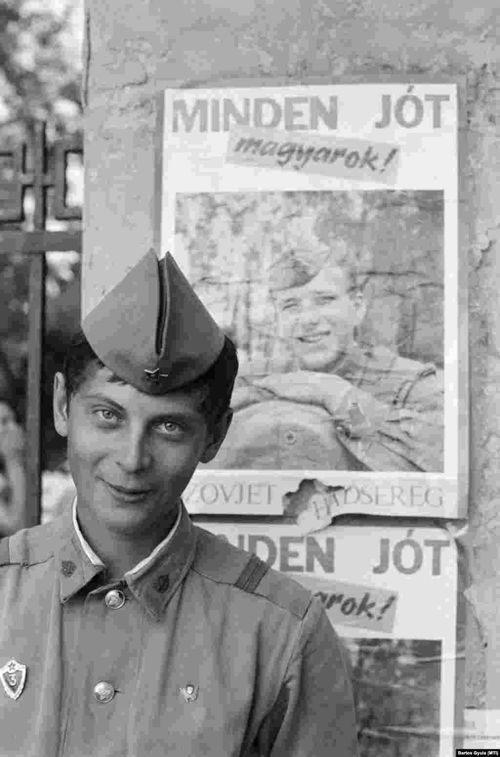 Budapest, 1990. május 18. Egy szovjet katona, mögötte a kivonuló szovjet hadsereg búcsúplakátja a pestújhelyi szovjet katonai kórház kerítésén.