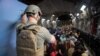 Американски военен наблюдава цивилни на борда на трансопртен самолет C-17 Глоубмастър по време на евакуацията от Афганистан