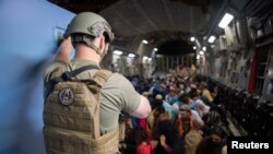 Американски военен наблюдава цивилни на борда на трансопртен самолет C-17 Глоубмастър по време на евакуацията от Афганистан