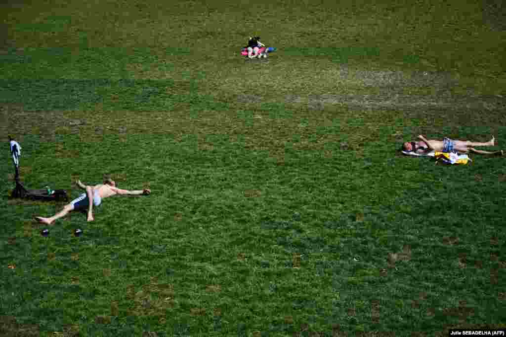 Луѓе се сончаат во јавниот парк Ла Вилет во Париз, 29 јуни.