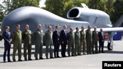 Secretarul general al NATO pozează cu mai multe oficialități și personal militar în fața unei drone fără pilot la Stadionul PGE National, locul de desfășurare a summitului NATO, Varșovia, 8 iulie 2016.