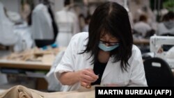 Egy alkalmazott dolgozik az Haute couture kollekcióján a Christian Dior párizsi központjában, 2021. július 3-án