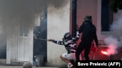 Demonstranti se skrivaju iza zida tokom sukoba nakon protesta protiv ustoličenja mitropolita Joanikija na Cetinju, 5. septembra 2021.