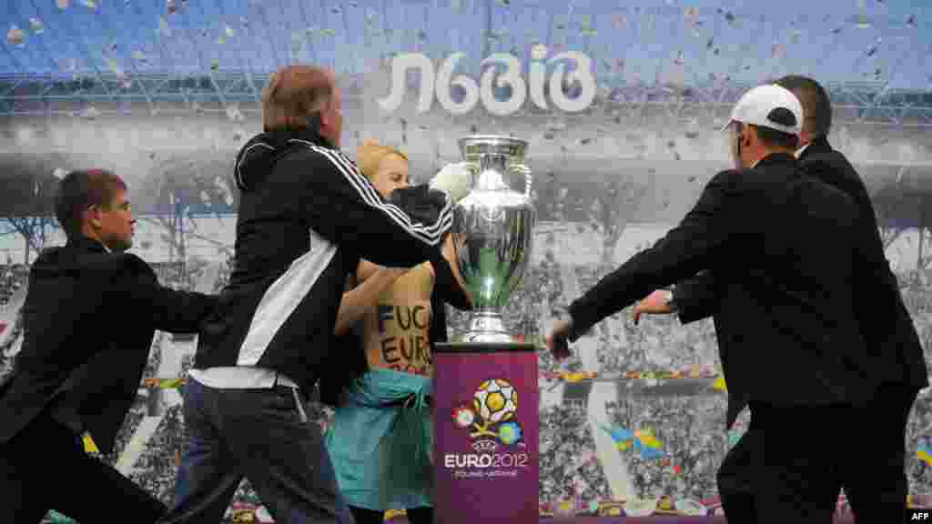 Ukraine -- An activist of women's movement FEMEN try to grab a Euro 2012 football championship trophy on display in the western city of Lviv, 24May2012