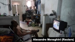 Un vânzător se uită la televizor în timpul discursului președintelui Miguel Diaz-Canel.