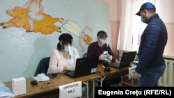 Operatori care verifică codul numeric personal la un centru de votare din Varnița. 1 noiembrie 2020 