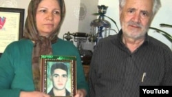 Akram Neghabi, standing next to her husband, Hashem Zeinali, holds a photograph of her son Saeed Zeinali, who has been missing since 1999.