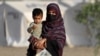 An Afghan woman holds a child as she arrives from Pakistan at a makeshift camp near the Afghanistan-Pakistan Torkham border in Nangarhar Province on April 20.
