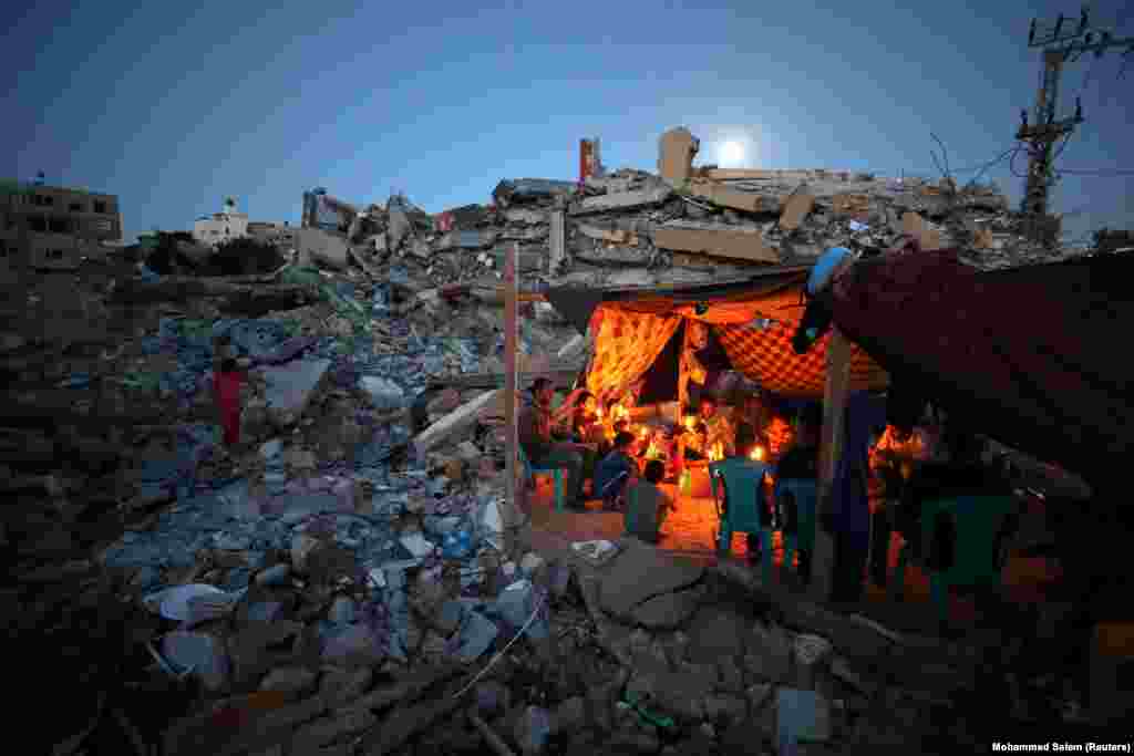 Palestinezët e familjes Zawaraa kanë ndezur qirinj dhe qëndrojnë në çadrën që kanë ngritur në rrënojat e shtëpive të tyre, që u shkatërruan nga sulmet ajrore të Izraelit, gjatë luftimeve mes Izraelit dhe palestinezëve në Gaza. 25 maj, 2021.
