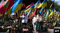 Семья молится перед могилой павшего украинского солдата на Лычаковском военном кладбище в Пасхальное воскресенье во Львове, 20 апреля 2025 года