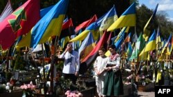 خانواده اوکراینی همزمان با عید پاک در حال دعا در برابر قبر یک سرباز کشته شده در جنگ؛ گورستان نظامی در شهر لویو