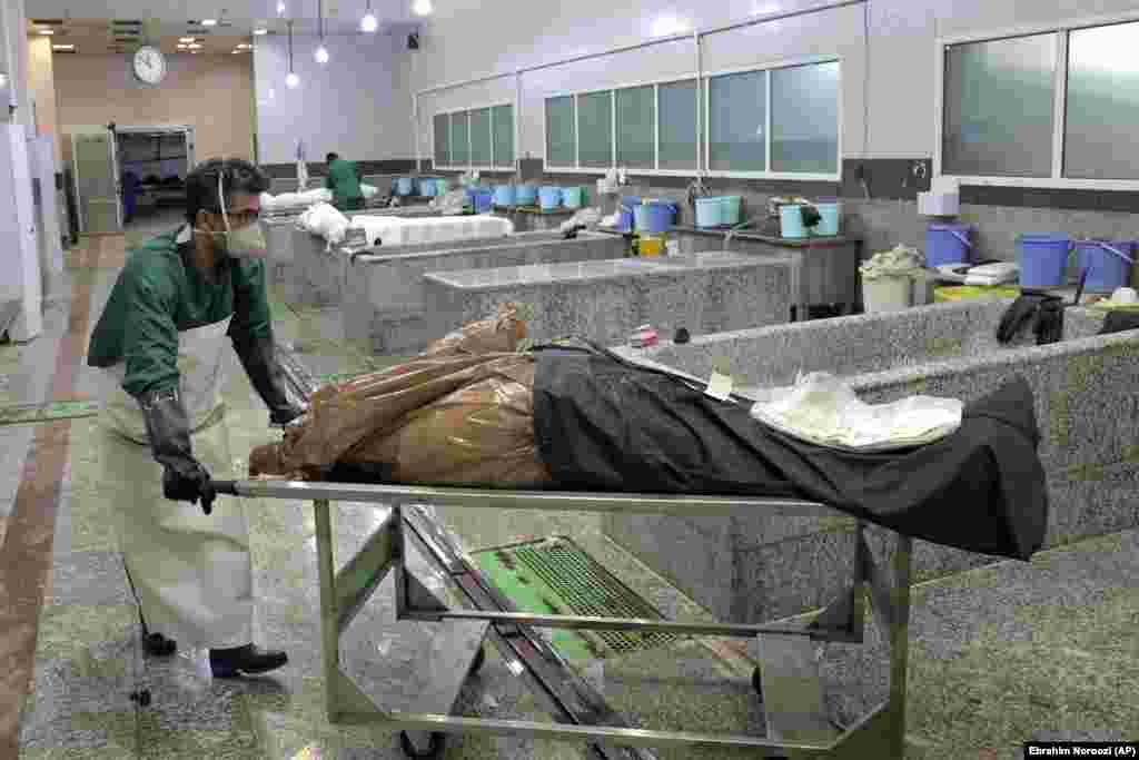 Un muncitor al cimitirului pregătește cadavrul unei persoane care a murit din cauza COVID-19, pentru înmormântare la cimitirul Behesht-e-Zahra,lângă Teheran, Iran, miercuri, 21 aprilie 2021. (Foto AP / Ebrahim Noroozi)