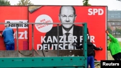 Radnici uklanjaju poster predizborne kampanje s liderom Socijaldemokratske partije (SPD) i najvećim kandidatom za kancelara Olafa Scholza, dan nakon opštih izbora u Njemačkoj, u Bad Segebergu kod Hamburga, 27. septembra 2021.