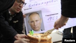Орусия -- Оппозиция активисттери президент Путиндин сүрөтү чапталган пенсионердик карточканын алдында торт кесип жатат. Москва, 7-октябрь, 2012.