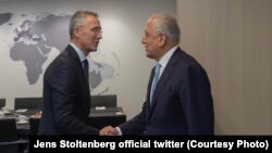NATO Secretary-General Jens Stoltenberg (left) shakes hands with Zalmay Khalilzand at NATO headquarters in Brussels on October 21.