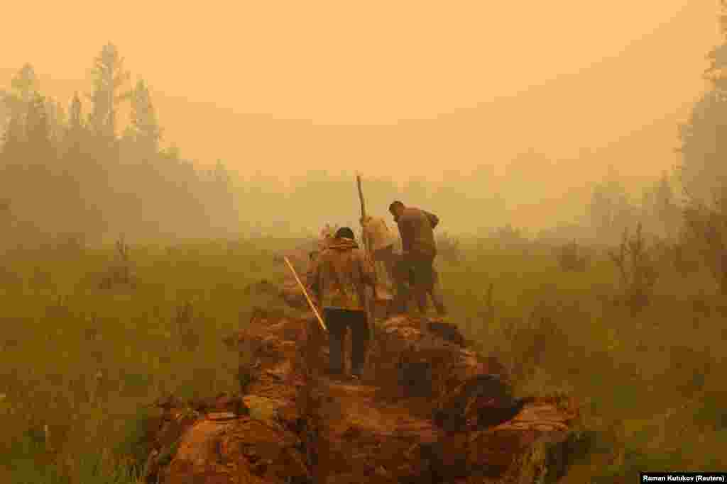 Vatrogasci i volonteri kopaju kontrolni kanal u pokušaju zaustavljanja požara, 17. jul