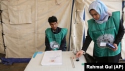 Afghan employees of the Independent Election Commission wait to register residents at a voter-registration center for the upcoming parliamentary and district council elections in Kabul last month.