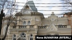 На грустном фоне пасмурного неба светло-коричневое здание с белыми окнами выглядит особенно впечатляюще