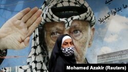 Jasszer Arafat egykori palesztin vezetőt ábrázoló plakát előtt sétál el egy járókelő a libanoni Shatila palesztin menekülttáborban, 2020. március 30-án.
