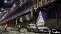 ماموران پلیس کی‌یف در حال ارزیابی خسارات وارد شده به اطراف یک فروشگاه پس از حمله پهپادی بامداد یکشنبه