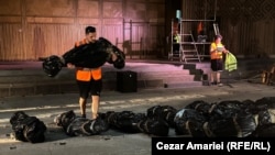 Un actor poartă pe brațe un sac simbolizând o posibilă victimă a unui nou cutremur