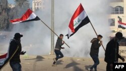 U.S. forces (unseen) fire teargas canisters at supporters and members of the Hashed al-Shaabi paramilitary force during a demonstration outside the US embassy in the Iraqi capital Baghdad on January 1, 2020.