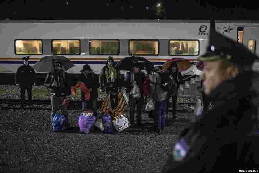 Një grup migrantësh pakistanezë qëndrojnë pranë binarëve hekurudhor pasi u nxorën jashtë një treni nga policia e Bosnjës.&nbsp;