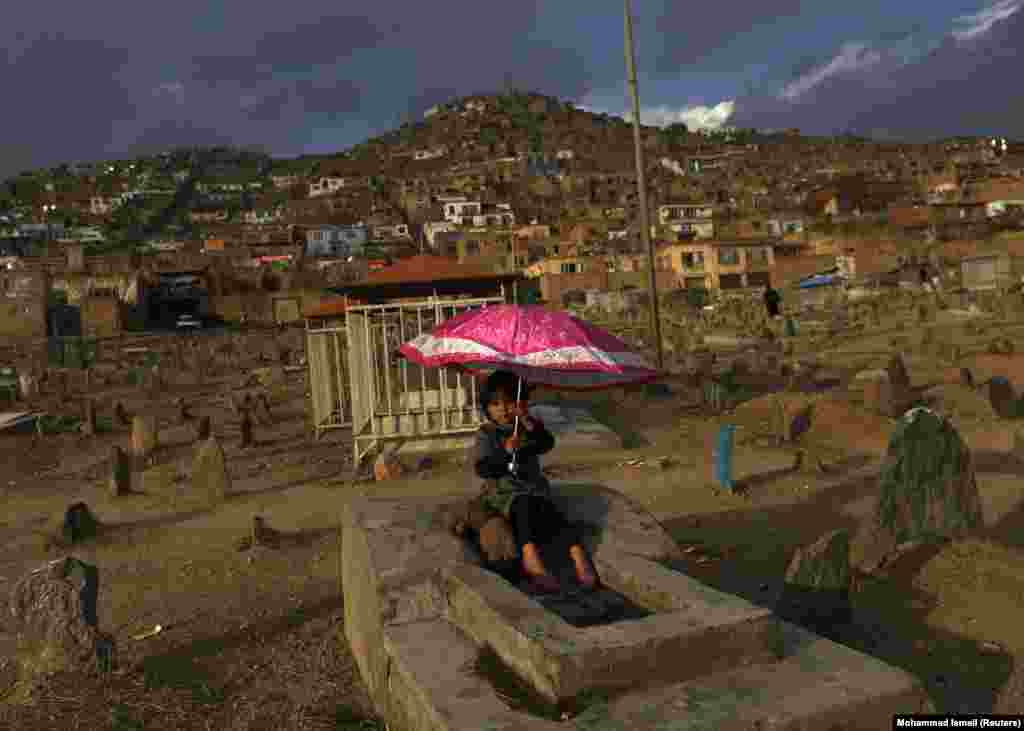 Девојче држи чадор на гробиштата. (Кабул, 12 февруари 2015 година)