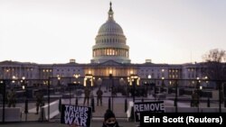Egy tüntető Trump-ellenes plakátokat mutat fel az amerikai Capitolium közelében, Washingtonban, 2021. január 12-én.