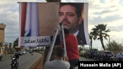 حامیان سعد حریری در حال نصب بنری در یکی از خیابان‌های بیروت که بر روی آن ذکر شده «همه ما سعد هستیم».