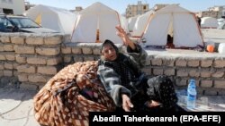 An elderly Iranian woman sits near tents erected for victims of the earthquake in the city of Sarpol-e Zahab in Kermanshah Province on November 14.
