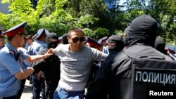 Қазақстандағы наразылық шарасына қатысушыны ұстап жатқан полиция. Көрнекі сурет