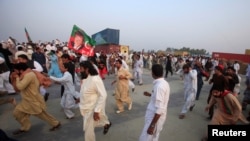 Supporters of Pakistani opposition leader Imran Khan run from tear gas as clashes begin between police and protesters in Swabi on October 31.