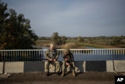 Українські солдати відпочивають на мосту через річку Оскіл після звільнення Куп'янська. 1 жовтня 2022 року