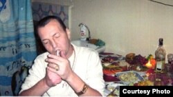 Азиз Батукаев Нарындагы абакта жайыл дасторкондун четинде отурат.(качан тартылганы белгисиз)