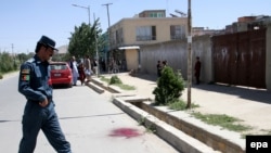 FILE: An Afghan Police officer inspects the scene of a bomb blast that targeted a police vehicle in Ghazni, June 2017.