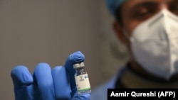 Медработник показывает ампулу с китайской вакциной Sinopharm. 
