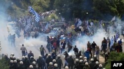 Протестувальники тримають прапор Греції під час сутичок з поліцією неподалік Пісодері, 17 червня 2018