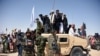 FILE: Afghan Taliban militants and residents stand on a armored Humvee vehicle of the Afghan National Army (ANA) as they celebrate a ceasefire on the third day of Eid in Maiwand district of Kandahar Province in June 2018.