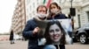 Nazanin Zaghari-Ratcliffe's husband, Richard Ratcliffe, and her daughter pose with a picture of her in London.