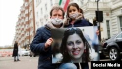 Nazanin Zaghari-Ratcliffe's husband, Richard Ratcliffe, and her daughter pose with a picture of her in London.