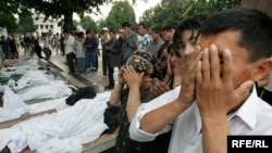 Люди молятся около тел жертв расстрела в Андижане. 14 мая 2005 года.
