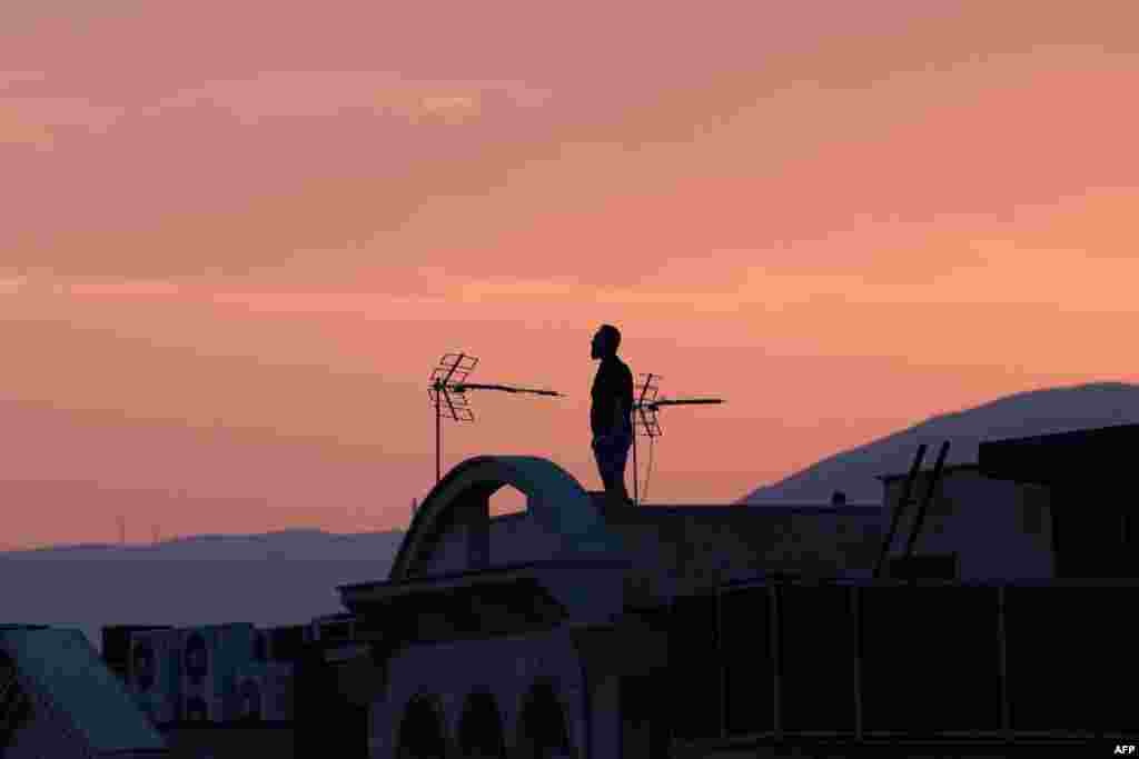 Мужчина стоит на крыше здания, наблюдая за горизонтом в Тегеране 16 июня 2025 года. ATTA KENARE / AFP