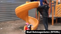 Алматы аулаларының бірінде баланы ойнатып тұрған келіншек. Алматы, 7 сәуір 2012 жыл. (Көрнекі сурет)