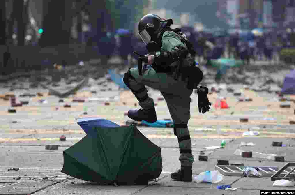 Співробітник спецпідрозділу поліції розтоптує парасольку, яку використовували продемократичні протестувальники під час сутичок біля Гонконгського політехнічного університету, 18 листопада 2019 року