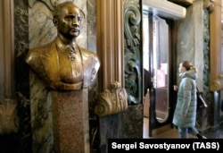 Покупательница направляется в Елисеевский, проходя мимо бюста его основателя, в последний день работы магазина. 11 апреля 2021 года.