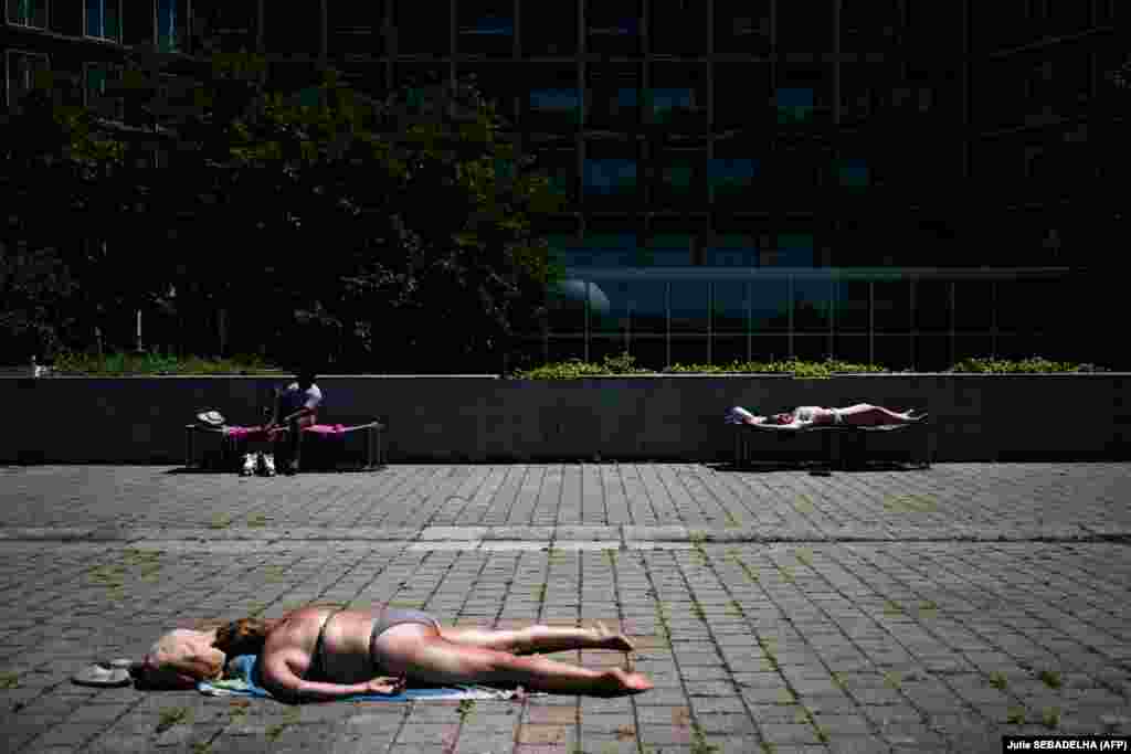 Луѓе се сончаат во Паркот Андре-Ситроен во Париз, 29 јуни.