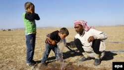 Сирия качкындары Түркия менен чектеш жерде суу ичүүдө. 26-сентябрь, 2014-жыл.