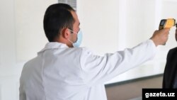Врач проводит контроль термодатчиком для определения температуры у гражданина Узбекистана. Фото с сайта Gazeta.uz.
