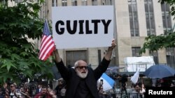 Muškarac drži plakat s natpisom "kriv" ispred krivičnog suda na Manhattanu u New Yorku, 30. maja 2024., nakon presude bivšem predsjedniku Donaldu Trumpu.